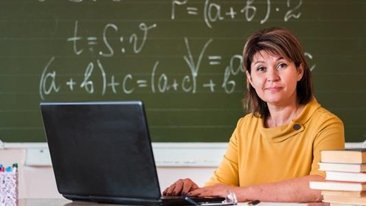 female teacher in yellow shirt with laptop working
