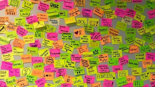 Many colorful post-it on a wall with lots of ideas written and drawn on them